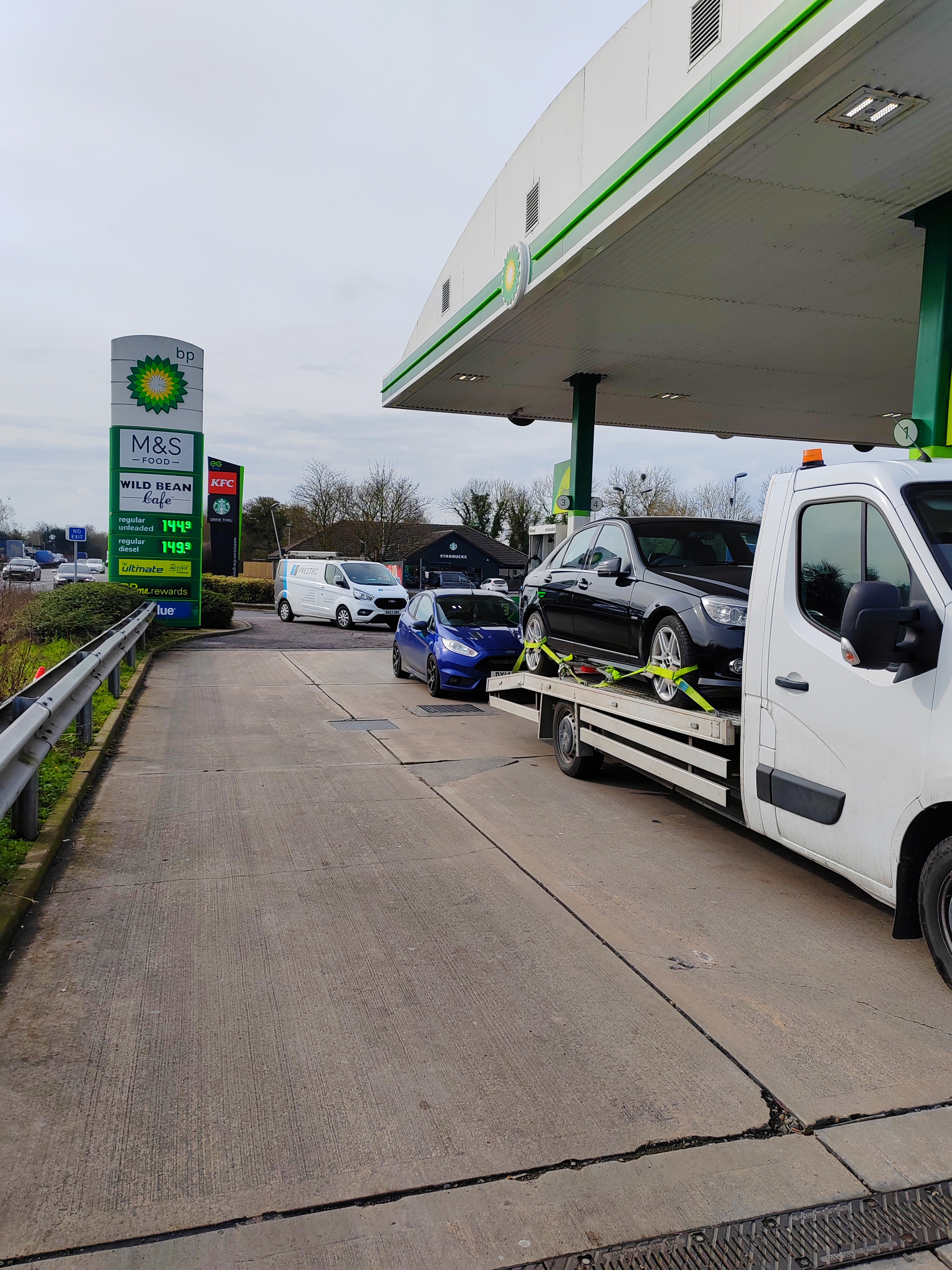 ANYTOW recovery truck collecting a vehicle near a service station