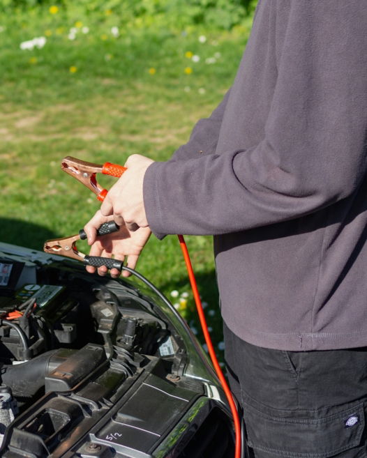 person in gray jacket standing beside black motorcycle